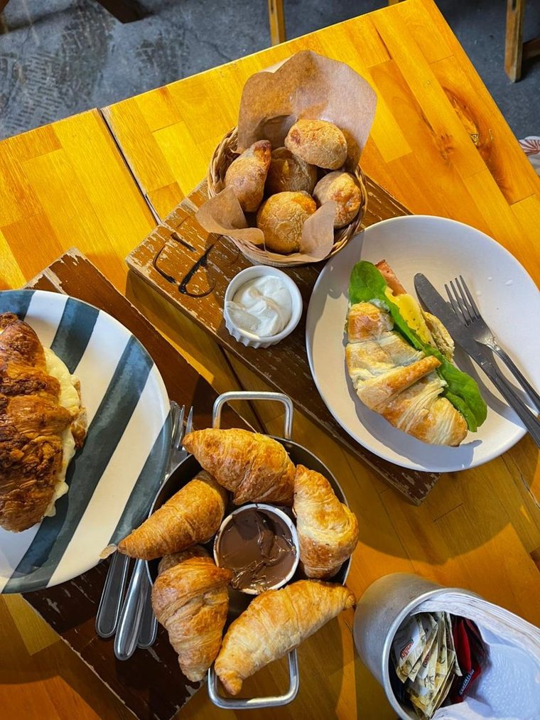 Mesa servida com croissants, salgados e sanduíche.
