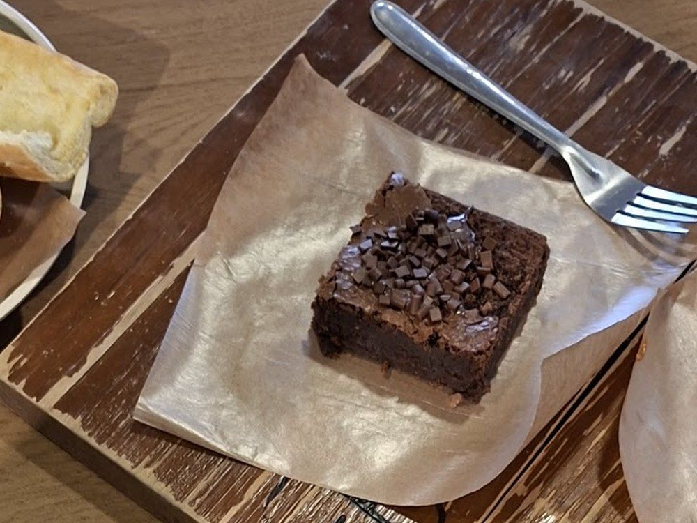 Brownie da Eba Brownie servido na tábua com café.